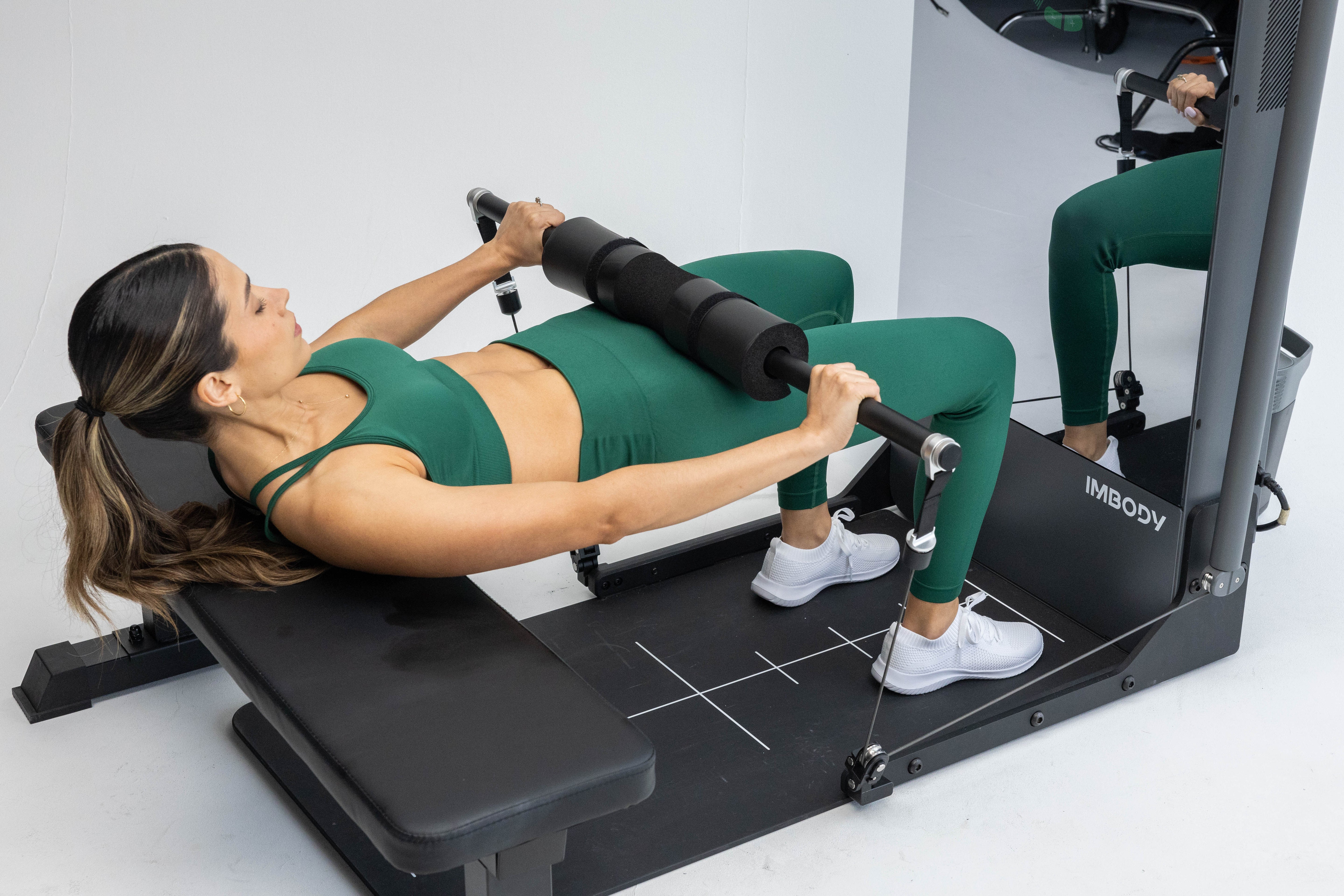 Person adjusting digital resistance on the IMBODY Power S smart home gym during a strength training workout